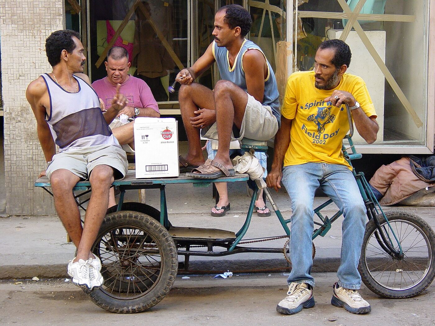 Hombres sentados en una calle de Centro Habana junto a un carrito de bicicleta