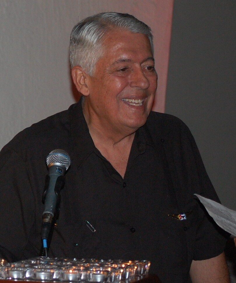 José Basulto, con el pelo canoso, sonríe ante un micrófono