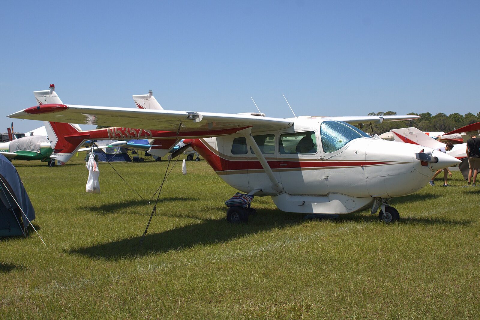 Una avioneta Cessna 337 Skymaster blanca y roja aparcada en la hierba de un aeródromo