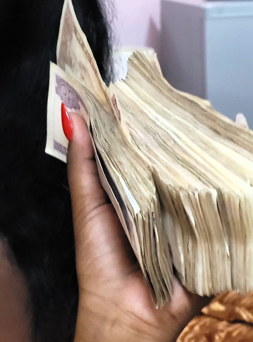 Una mano sostiene un fajo grueso de billetes de pesos cubanos
